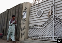 FILE - A man looks at graffiti supporting the Islamic State group as he walks past an entrance of a compound in Karachi, Pakistan, Nov. 12, 2014.