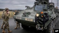 ທະຫານ ຢືນຢູກັບລົດຫູ້ເກາະ Stryker ຢູ່ເມືອງ Vilseck ປະເທດເຢຍຣະັມນ ວັນທີ 9/ ກຸມພາ 2022.