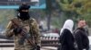 Луѓе поминуваат покрај бунтовнички борец кој чува стража на плоштад, откако бунтовниците го зазедоа главниот град и го соборија претседателот Башар ал-Асад, во Дамаск, Сирија, 11 декември 2024 година