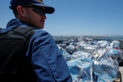 Seorang agen penjaga pantai AS mengawasi lebih dari 13 ton kokain yang disita di lepas pantai Meksiko dan Amerika Selatan Tengah sebelum diturunkan dari Coast Guard Cutter Steadfast di pelabuhan di San Diego, California, AS, 26 Juli 2019. (Foto: REUTERS)