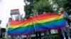 FILE – LGBTQ+ activists wave flags at a rally in Moscow on July 15, 2020. 