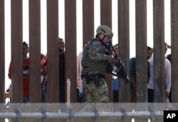 FILE - A U.S. Customs and Border Protection officer walks along a wall at the border between Mexico and the United States, as seen from San Diego, California, Nov. 25, 2018.