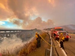 Petugas pemadam kebakaran berupaya memadamkan api kebakaran di tepi Highway 101 menuju selatan Vista Point, Selasa sore, 12 Oktober 2021.