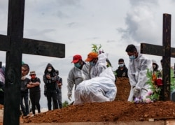 Penggali kubur mengenakan alat pelindung diri (APD) di area pemakaman yang disediakan pemerintah untuk korban COVID-19, seiring lonjakan kasus di Jayapura, Papua, 20 Juli 2021. (Foto: Antara/Indrayadi TH via REUTERS)
