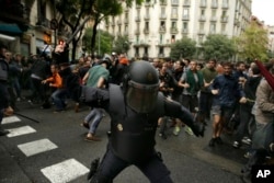 Na ovoj fotografiji od 1. oktobra, španska policija za razbijanje demonstracija koristi palice protiv ljudi koji su želeli da glasaju, u blizini škole koju je katalonska vlada predvidela da bude glasačko mesto, u Barseloni, Španija