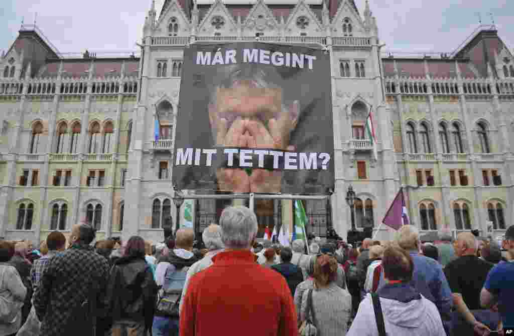 A man holds a poster of Hungarian Premier Viktor Orban that reads "What have I done again" during a protest by opposition parties against Orban's policies on migrants in Budapest, Hungary. Hungarians vote in a referendum which the prime minister hopes will give his government the popular support it seeks to oppose any future plans by the European Union to resettle asylum seekers among its member states.