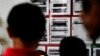FILE - Migrants seeking asylum in the United States check their names on a printed list that's posted on a board near the international bridge, April 30, 2019, in Matamoros, Mexico.
