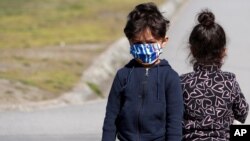 Deca migranata nose maske kako bi se zaštitila od zaraze Kovidom 19, tokom vakcinacije u centru za izbeglice u Krnjači, u Beogradu, 26. marta 2021. Srbija je započela sa vakcinacijom migranata. (Foto: AP)