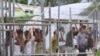 FILE - Asylum-seekers look through a fence at the Manus Island detention center in Papua New Guinea, March 21, 2014. 