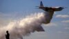 A television reporter stands in front of a Large Air Tanker (LAT) C-130 Hercules, also known as ‘Thor,’ as it drops a load of around 15,000 liters of retardant during a display ahead of the bushfire season, at RAAF Base Richmond, Sydney, Australia, Sept. 1, 2017.