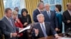 President Donald Trump looks toward Budget Director Mick Mulvaney, left, after signing an executive order in the Oval Office of the White House in Washington, March 13, 2017. 
