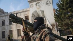 Seorang anggota pasukan oposisi Suriah membawa peluncur roket saat berada di depan sebuah gedung kantor pemerintahan di mana terdapat foto Presiden Bashar Assad yang dipenuhi robekan akibat tembakan di Hama, Suriah, pada 6 Desember 2024. (Foto: AP/Ghaith Alsayed)