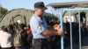 Croatian police guard a camp near the border they say will house refugees for a day or two before they are transferred to the border with Hungary, Opatovac, Croatia, Sept. 21, 2015. (VOA / H. Murdock) 