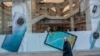 A woman and her dog walk past a Huawei shop in Madrid, Feb. 20, 2020. The top U.S. diplomat for cybersecurity policy warned that the U.S. will not be able to share information at top levels with countries that go with “untrusted” vendors, such as Huawei.
