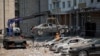 Pegawai dinas kota memindahkan mobil yang hancur dari tempat parkir di sebelah gedung apartemen yang rusak berat selama serangan drone Rusia besar-besaran, di tengah serangan Rusia terhadap Ukraina, di Kyiv, Ukraina 30 Mei 2023. (Foto: REUTERS/Alina Smutko)
