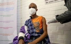 Seorang sukarelawan menerima suntikan dari seorang pekerja medis selama uji klinis manusia pertama di negara itu untuk vaksin potensial melawan virus corona baru, di Soweto. (Foto: Reuters)