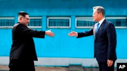 김정은 북한 국무위원장(왼쪽)과 문재인 한국 대통령이 군사분계선을 사이에 두고 손을 내밀고 있다.