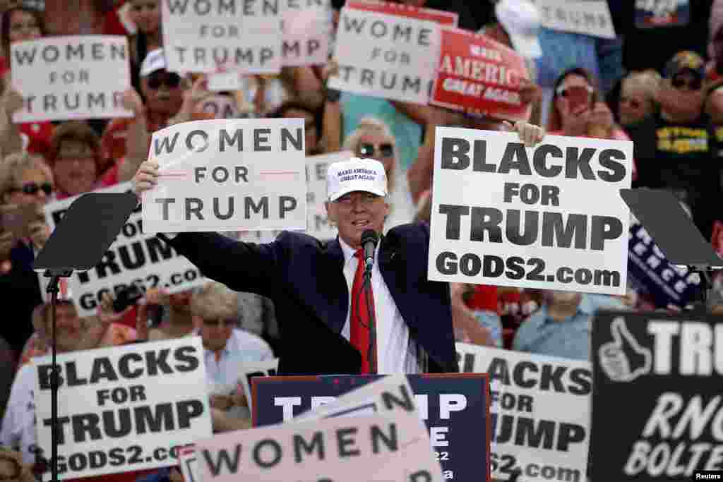 Republican presidential nominee Donald Trump holds up signs at the end of a campaign rally in Lakeland, Florida, U.S., Oct. 12, 2016.