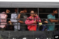 Buruh migran Kamboja berdiri di atas truk saat mereka tiba dari Thailand di gerbang perbatasan internasional Kamboja-Thailand di Poipet, Kamboja, Selasa, 17 Juni 2014. (Foto: AP)