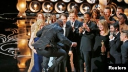Director and producer Steve McQueen jumps after accepting the Oscar for best picture for his work in "12 Years a Slave" at the 86th Academy Awards in Hollywood, CA, March 2, 2014.