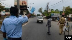 Personel polisi dan sukarelawan sipil menghentikan kendaraan di pos pemeriksaan saat berlangsungnya karantina nasional yang diberlakukan pemerintah sebagai tindakan pencegahan terhadap penyebaran virus COVID-19, di Siliguri, India, 13 April 2020. (Foto oleh DIPTENDU DUTTA / AFP)
