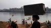 FILE - An unidentified woman carries her belongings on her head after crossing the Mbomou River, which forms part of the boundary between the Central African Republic and the Democratic Republic of the Congo, Feb. 14, 2021.