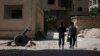 FILE - Fighters from the Free Syrian Army's Al Rahman legion walk toward their positions in Jobar, a suburb of Damascus, Syria.