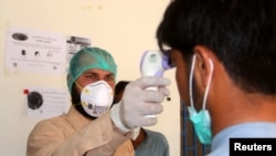 A health worker takes the temperature of a man who returned from Iran and is under medical observation, after Pakistan sealed its border with Iran as a preventive measure following the coronavirus outbreak, at the border post in Taftan, Pakistan…