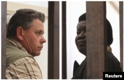 Pengelola tur safari Honest Ndlovu (kanan) dan pemandu pemburu Theo Bronkhorst menanti sebelum menghadap pengadilan di Hwange, Zimbabwe (29/7).