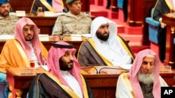 Photo provided by the Saudi Press Agency, SPA, Crown Prince Mohammed bin Salman (front left) seated next to the country’s most senior cleric, listens to Saudi King Salman give his annual policy speech in the ornate hall of the consultative Shura Council,