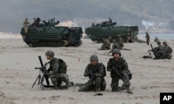 South Korean Marines and U.S. Marines from 3rd Marine Expeditionary Force based Okinawa, Japan, take positions near Amphibious Assault Vehicle (AAV) during the U.S.-South Korea joint military exercises called Ssangyong 2013 as part of their two-month-long
