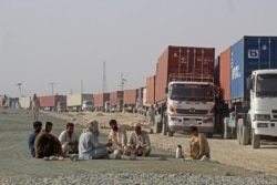 Para pengemudi beristirahat di dekat truk kontainer mereka, menunggu di kota perbatasan Chaman, Pakistan, untuk memasuki Afghanistan, 30 Agustus 2021. ( AFP)