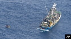 This photo released by the New Zealand Defence Force shows a wooden dinghy, left, carrying seven survivors from a missing ferry and a fishing boat in the Pacific Ocean, Jan. 28, 2018.