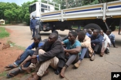 FILE - A policeman stands guard as some of the people arrested during demonstrations over the hike in fuel prices, make their court appearance at the magistrates courts in Harare, Zimbabwe, Jan,16, 2019.