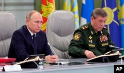 Russian President Vladimir Putin, left, and Chief of General Staff of Russia Valery Gerasimov oversee the test launch of the Avangard hypersonic glide vehicle from the Defense Ministry's control room in Moscow, Russia, Wednesday, Dec. 26, 2018.