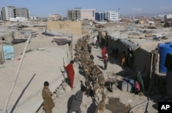 FILE - Afghan boy shepherds walk their sheep near temporary housing in Kabul, Afghanistan, May 30, 2016.