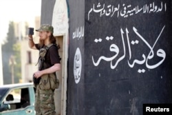 FILE - A militant Islamist fighter uses a mobile to film his fellow fighters taking part in a military parade along the streets of Syria's northern Raqqa province.