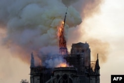 The steeple and spire of the landmark Notre Dame Cathedral collapses as the cathedral is engulfed in flames in central Paris, April 15, 2019.