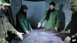 FILE - This undated photo released by a militant group in 2016, shows Abu Mohammed al-Golani of the militant Levant Liberation Committee and the leader of Syria's al-Qaida affiliate, second right, discussing battlefield details with field commanders over map, in Aleppo, Syria.