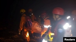 Rescue workers carry a body bag containing a victim following the collapse of an illegal gold mine at Bolaang Mongondow regency in North Sulawesi, Indonesia, Feb. 26, 2019.