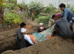 Gayesh Ansari, looks at the body of his 8 months pregnant wife, Gulshan Ansari as he lowers her body into a grave after she died from the coronavirus disease (COVID-19) at a graveyard in Mumbai, India April 28, 2021. Picture taken April 28, 2021. REUTERS/
