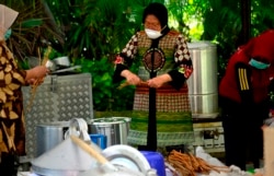 Wali Kota Surabaya Tri Rismaharini terlibat dalam aktivitas penyediaan minuman dan makanan tambahan di dapur umum. (Foto: VOA/Petrus Riski)