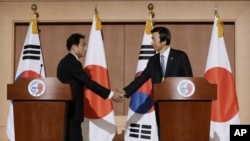 Menteri Luar Negeri Korea Selatan Yun Byung-se, kanan, berjabat tangan dengan Menteri Luar Negeri Jepang Fumio Kishida setelah konferensi pers gabungan di Kementerian Luar Negeri di Seoul, Korea Selatan, Senin, 28 Desember 2015.