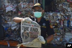 Seorang petugas menunjukkan surat kabar asing yang ditemukan diantara sampah dalam kontainer di Tanjung Perak, Surabaya. (Foto: AP)