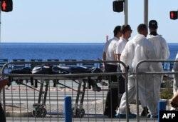 Forensics experts evacuate a dead body on the Promenade des Anglais seafront in the French Riviera town of Nice on July 15, 2016, after a gunman smashed a truck into a crowd of revelers celebrating Bastille Day.