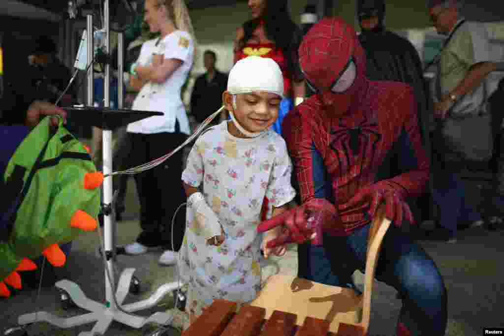 Mattel Children's Hospital UCLA patient Gael Martin, 5, (L) meets a window washer dressed as Spider-Man in Los Angeles, California, Sept. 14, 2016.