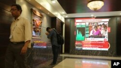 A man offers prayer to a Hindu goddess at the Bombay Stock Exchange (BSE) office, as India's Finance Minister Nirmala Sitharaman is seen on a television screen presenting the annual budget in Mumbai, India, July 5, 2019. 