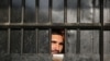 Taliban prisoners watch through the door inside a prison after an attack in the city of Jalalabad, east of Kabul, Afghanistan, Aug. 3, 2020.
