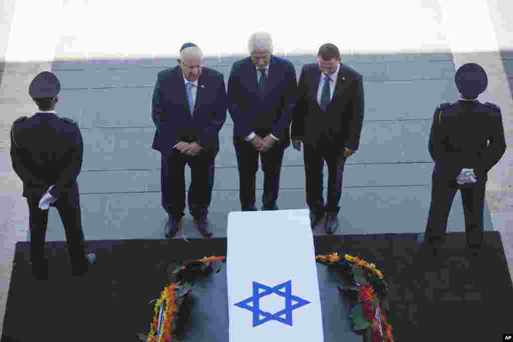 Former US President Bill Clinton, center, accompanied by Israel's President Reuven Rivlin, left, and Yuli Edelstein, the Speaker of the Knesset, pays respects by the coffin of former Israeli President Shimon Peres at the Knesset plaza in Jerusalem, Sept.