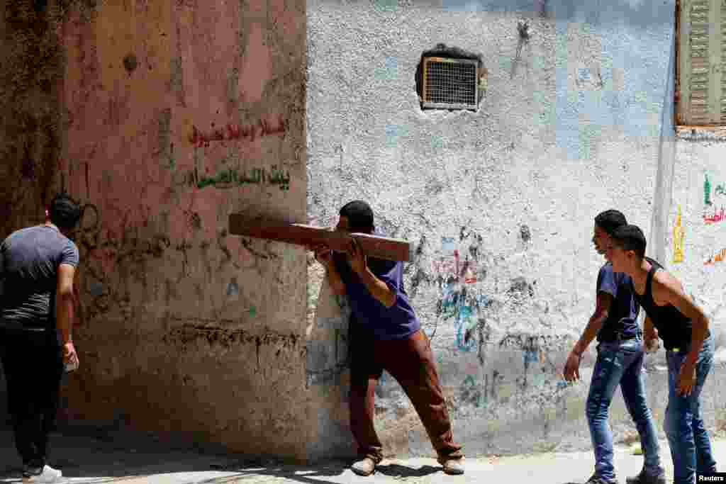 A Palestinian man points a plank at Israeli troops during clashes in the West Bank Al-Fawwar refugee camp, south of Hebron.